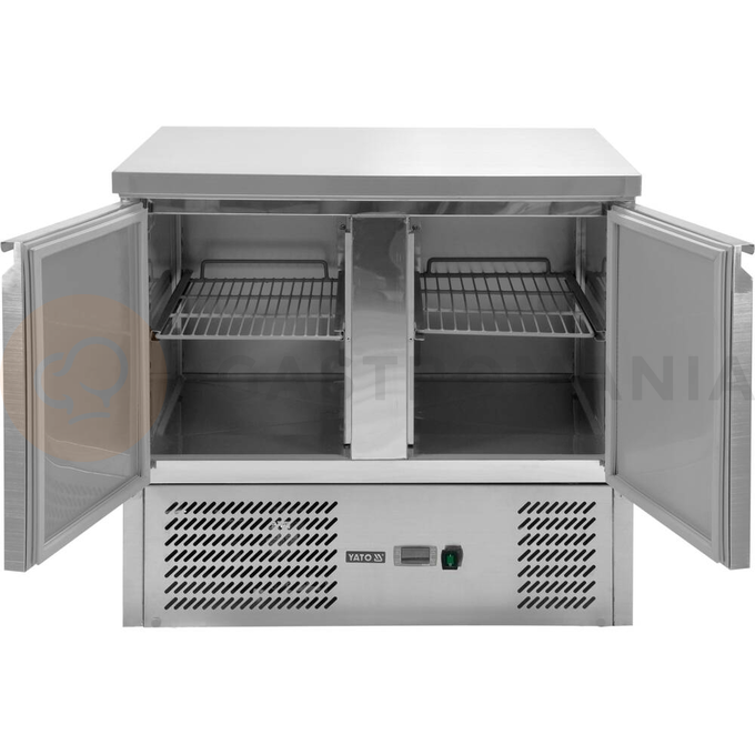Stół chłodniczy 2-drzwiowy z blatem roboczym marki YATO YG-05270.
Stół chłodniczy o wymiarach 900 x 700 x 870 mm ma pojemność komory 240 L.
Przeznaczony jest do przechowywania żywności w zakresie temperatur +2~+8°C. Doskonale nadaje się do wszelkiego typu punków gastronomicznych takich jak restauracje, bary, puby czy pizzerie.
Obudowa zewnętrzna i wewnętrzna wykonana z wysokiej jakości stali nierdzewnej SS201 gwarantuje elegancki wygląd, a jednocześnie jest bardzo łatwa w utrzymaniu w czystości.
Dolny agregat chłodniczy o mocy 170 W wykorzystuje czynnik chłodniczy R600a dedykowany do pracy w 4 klasie klimatycznej, przy maksymalnej temperaturze otoczenia 30°C i wilgotności względnej 55%. Zasilany jest prądem o napięciu 220-240 V  ~50 Hz. Średnie roczne zużycie energii 940 kWh.
Elektroniczny sterownik marki Dixell z cyfrowym wyświetlaczem temperatury.
Urządzenie posiada chłodzenie statyczne z obiegiem wymuszonym wentylatorem oraz funkcję automatycznego odszraniania.
Model z samozamykającymi się drzwiami wyposażonymi w zamek oraz wygodnymi uchwytami do otwierania. Na każde drzwi ma w zestawie po 1 półce rusztowej powlekanej PVC o nośności max 40 kg - przy równomiernym obciążeniu. Umożliwia przechowywanie pojemników GN 1/1.
 | YG-05270, Stół chłodniczy 2-drzwiowy - linia 700